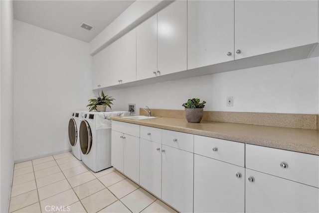 clothes washing area with cabinets, light tile patterned floors, separate washer and dryer, and sink