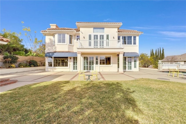 rear view of property with a yard, a balcony, and a patio area