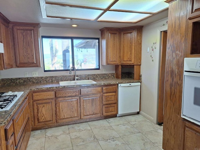 kitchen with dark stone countertops, sink, and white appliances