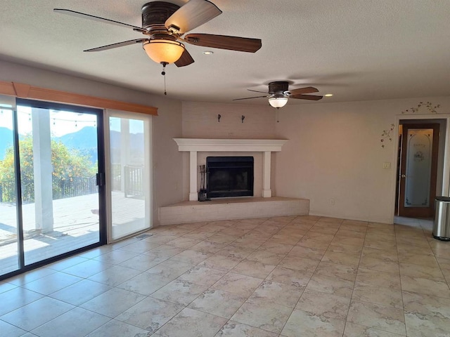 unfurnished living room with ceiling fan and a textured ceiling