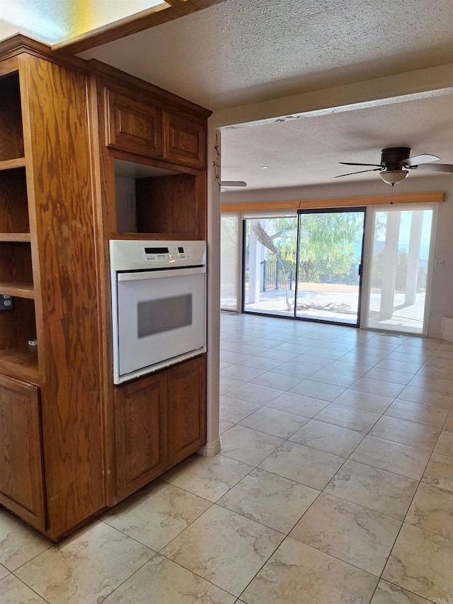 kitchen with ceiling fan, a textured ceiling, and white oven