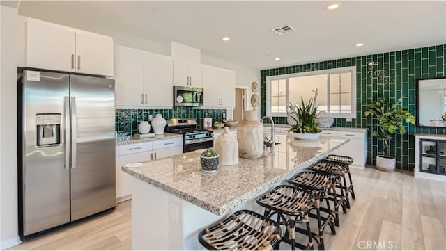 kitchen with light stone countertops, white cabinetry, and stainless steel appliances