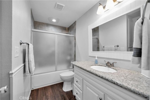 full bathroom featuring wood-type flooring, vanity, toilet, and enclosed tub / shower combo