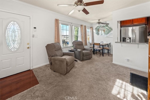 carpeted living room with ceiling fan and crown molding