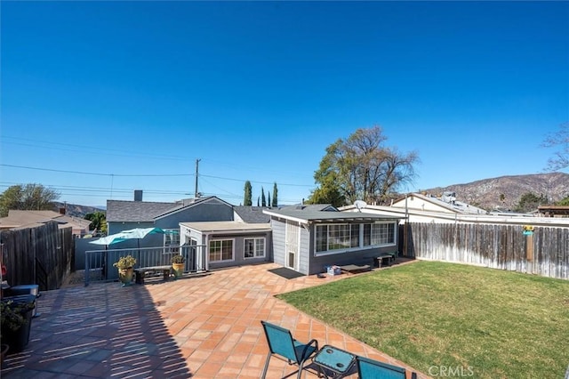 back of house with a patio area, a water and mountain view, and a yard