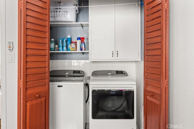 clothes washing area with cabinets and washing machine and clothes dryer