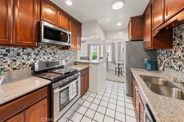 kitchen with stainless steel appliances, sink, tasteful backsplash, and light stone counters