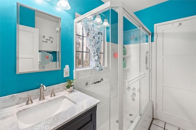 bathroom with a shower with door, vanity, and tile patterned floors