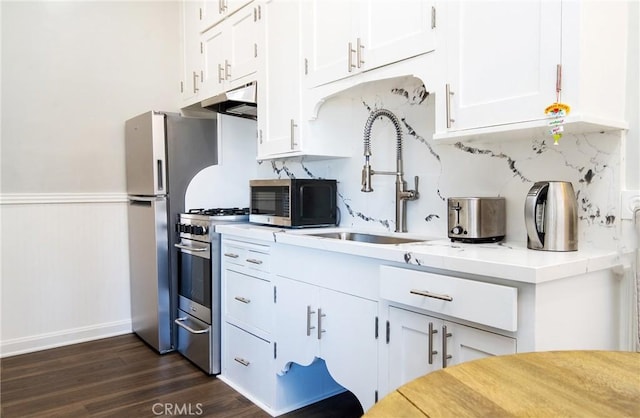 kitchen with sink, appliances with stainless steel finishes, white cabinets, backsplash, and dark wood-type flooring