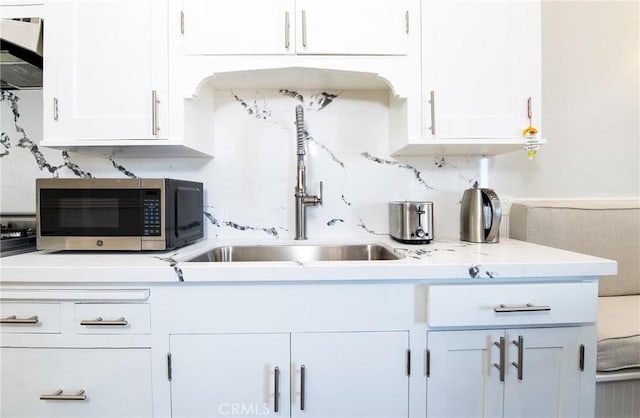 kitchen featuring sink, white cabinets, decorative backsplash, and exhaust hood