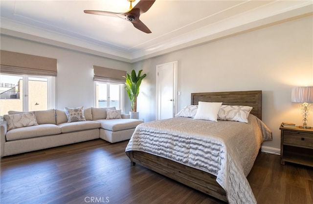 bedroom featuring ceiling fan, a tray ceiling, and dark hardwood / wood-style flooring