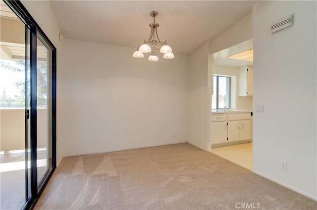 empty room with light carpet, sink, and a chandelier