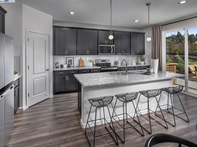 kitchen featuring a kitchen bar, light stone countertops, pendant lighting, and stainless steel appliances