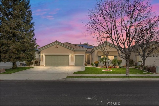 view of front of property featuring a lawn, a garage, and solar panels