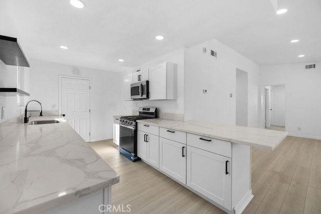 kitchen with stainless steel appliances, light stone counters, sink, light hardwood / wood-style flooring, and white cabinetry