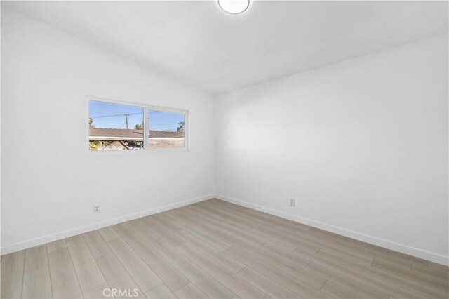 unfurnished room featuring light hardwood / wood-style floors and vaulted ceiling