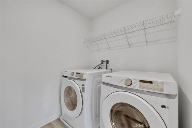 clothes washing area featuring separate washer and dryer and light hardwood / wood-style flooring