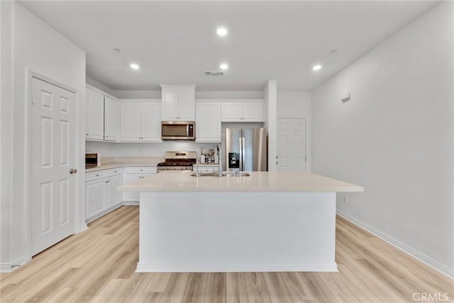 kitchen featuring stainless steel appliances, a center island with sink, light hardwood / wood-style flooring, and white cabinetry