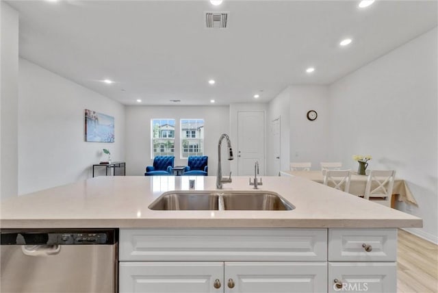 kitchen featuring dishwasher, white cabinetry, a center island with sink, sink, and light hardwood / wood-style flooring