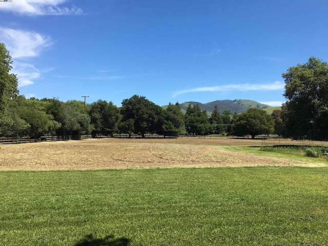 surrounding community with a mountain view, a rural view, and a lawn