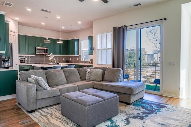 living room with ceiling fan, sink, and light hardwood / wood-style flooring