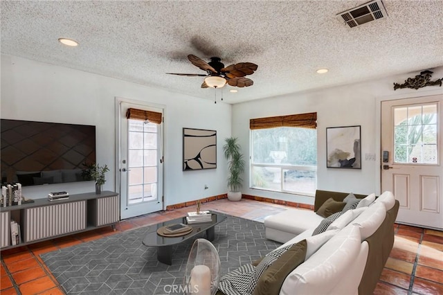 living room featuring a textured ceiling, ceiling fan, and dark tile patterned flooring