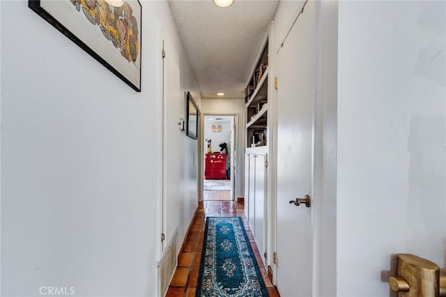 hall with a textured ceiling and tile patterned floors