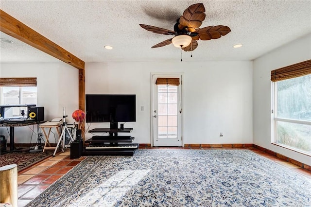 living room with a textured ceiling, ceiling fan, and beam ceiling