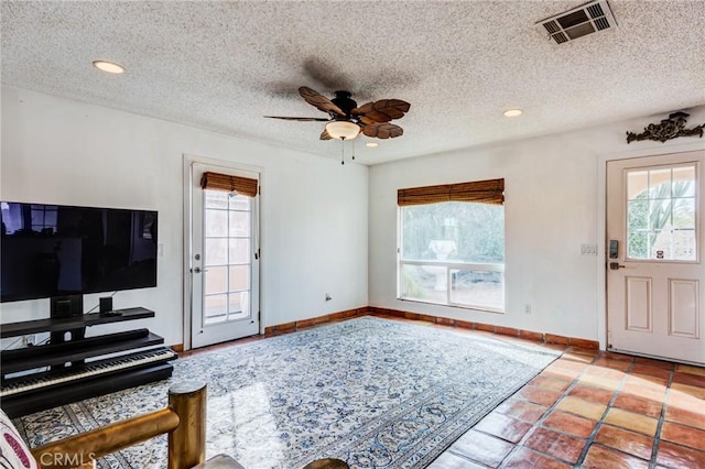 interior space with a textured ceiling, ceiling fan, and plenty of natural light