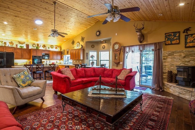 living room with hardwood / wood-style floors, high vaulted ceiling, a wood stove, and ceiling fan