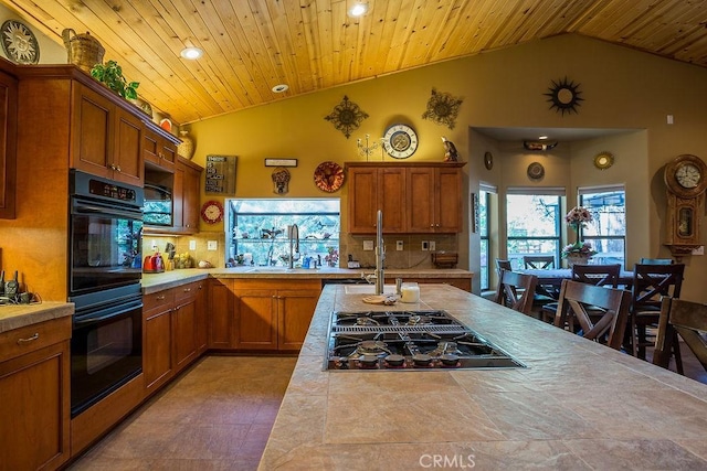 kitchen featuring black appliances, tile counters, backsplash, and vaulted ceiling