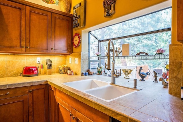 kitchen with decorative backsplash, tile countertops, a wealth of natural light, and sink