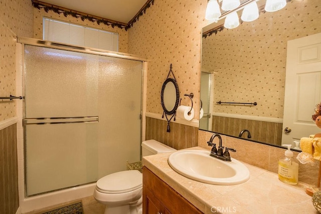 bathroom with vanity, wood walls, toilet, and a shower with shower door