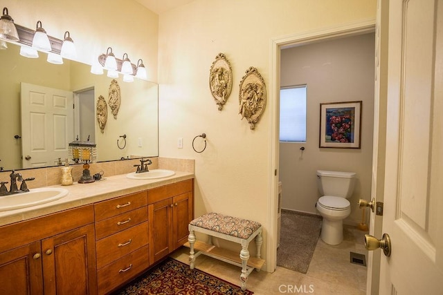 bathroom with toilet, vanity, and tile patterned floors