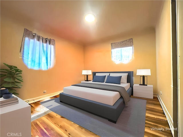 bedroom featuring hardwood / wood-style floors and a baseboard heating unit