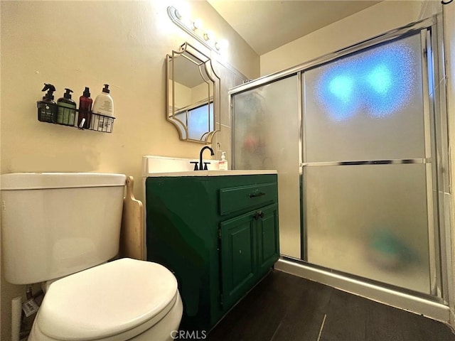 bathroom featuring toilet, vanity, hardwood / wood-style floors, and a shower with shower door