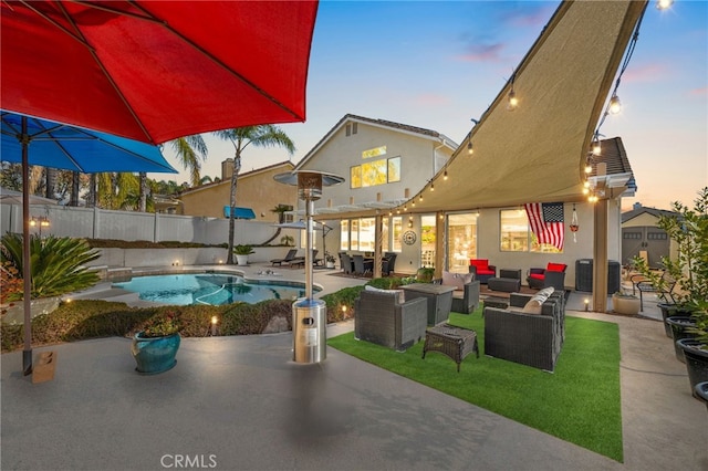 pool at dusk with a patio area and an outdoor living space