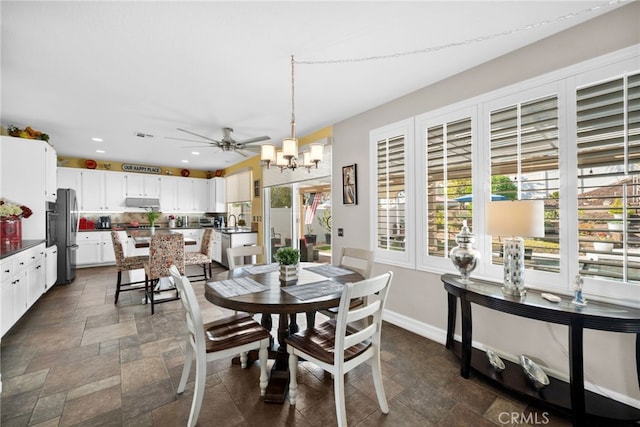 dining area featuring ceiling fan with notable chandelier and sink