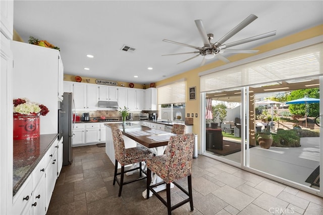 kitchen with sink, white cabinetry, ceiling fan, decorative backsplash, and stainless steel refrigerator