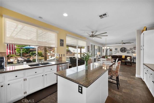 kitchen with sink, white cabinetry, a center island, dishwasher, and dark stone counters