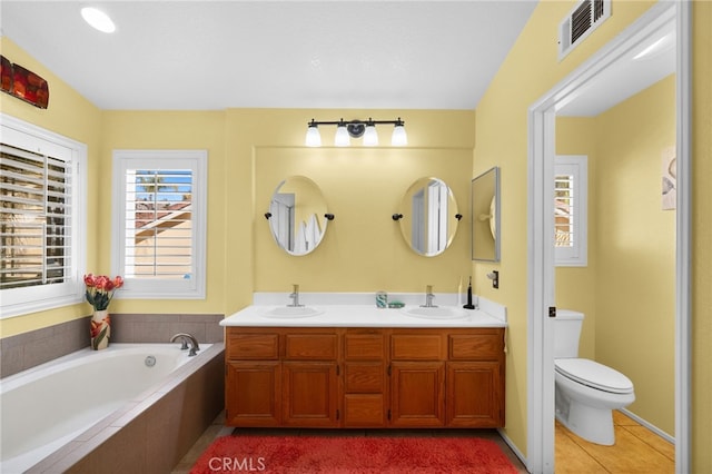 bathroom featuring toilet, vanity, tile patterned floors, and a relaxing tiled tub