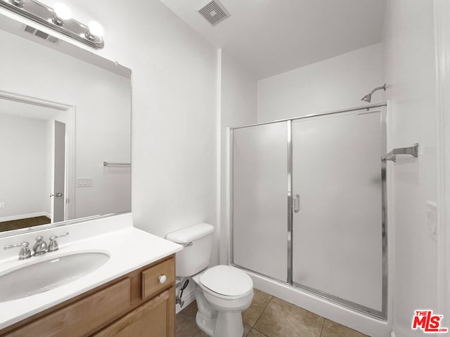 bathroom featuring tile patterned flooring, vanity, toilet, and walk in shower