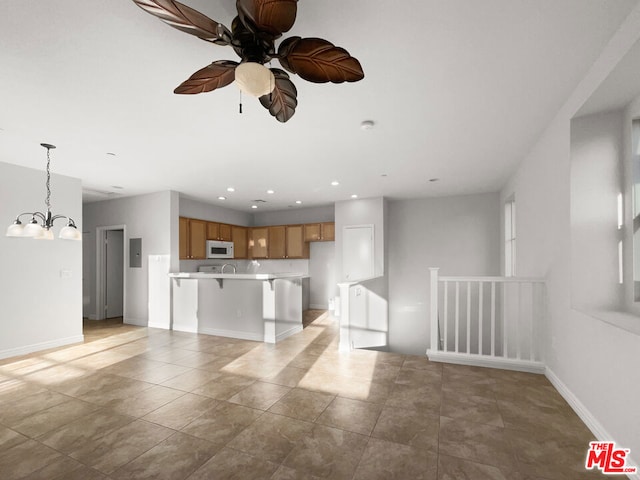 kitchen with a kitchen breakfast bar, ceiling fan with notable chandelier, light tile patterned flooring, and decorative light fixtures