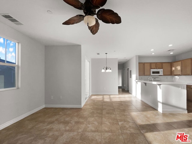 kitchen featuring dishwashing machine, light tile patterned floors, ceiling fan with notable chandelier, and hanging light fixtures