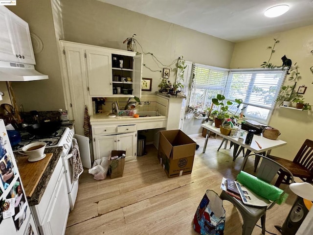 kitchen with white cabinets, white range with gas stovetop, and light hardwood / wood-style floors