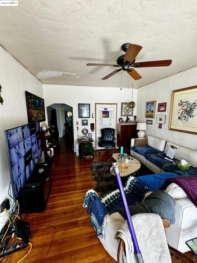 living room with a textured ceiling, ceiling fan, and dark hardwood / wood-style floors