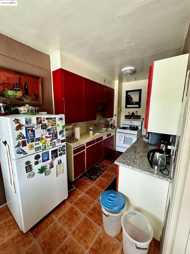 kitchen with white appliances, dark tile patterned floors, and sink