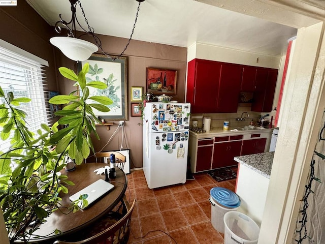 kitchen with decorative backsplash, white refrigerator, dark tile patterned flooring, and sink