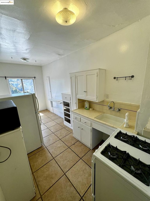 kitchen featuring white appliances, white cabinets, sink, light tile patterned flooring, and beverage cooler