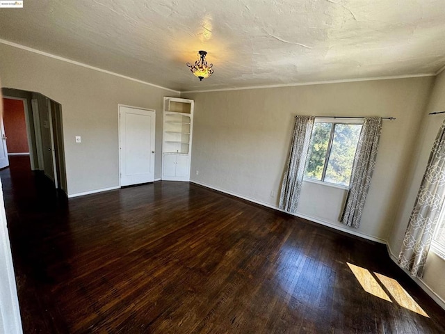 spare room featuring ornamental molding and dark wood-type flooring